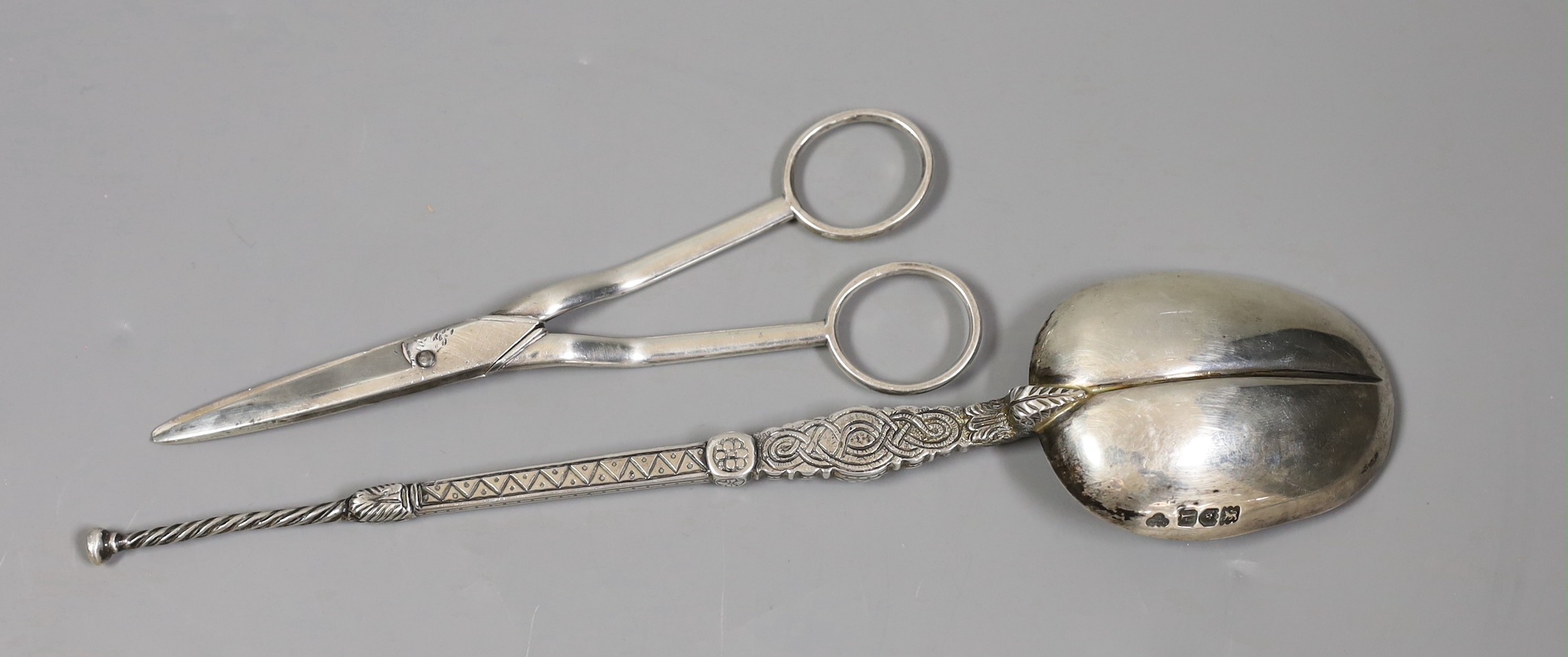 Pair of George III silver grape scissors, by Eley & Fearn, London, 1818 and a George V silver replica of the anointing spoon, Goldsmiths & Silversmiths Co Ltd, London 1910, 166 grams.